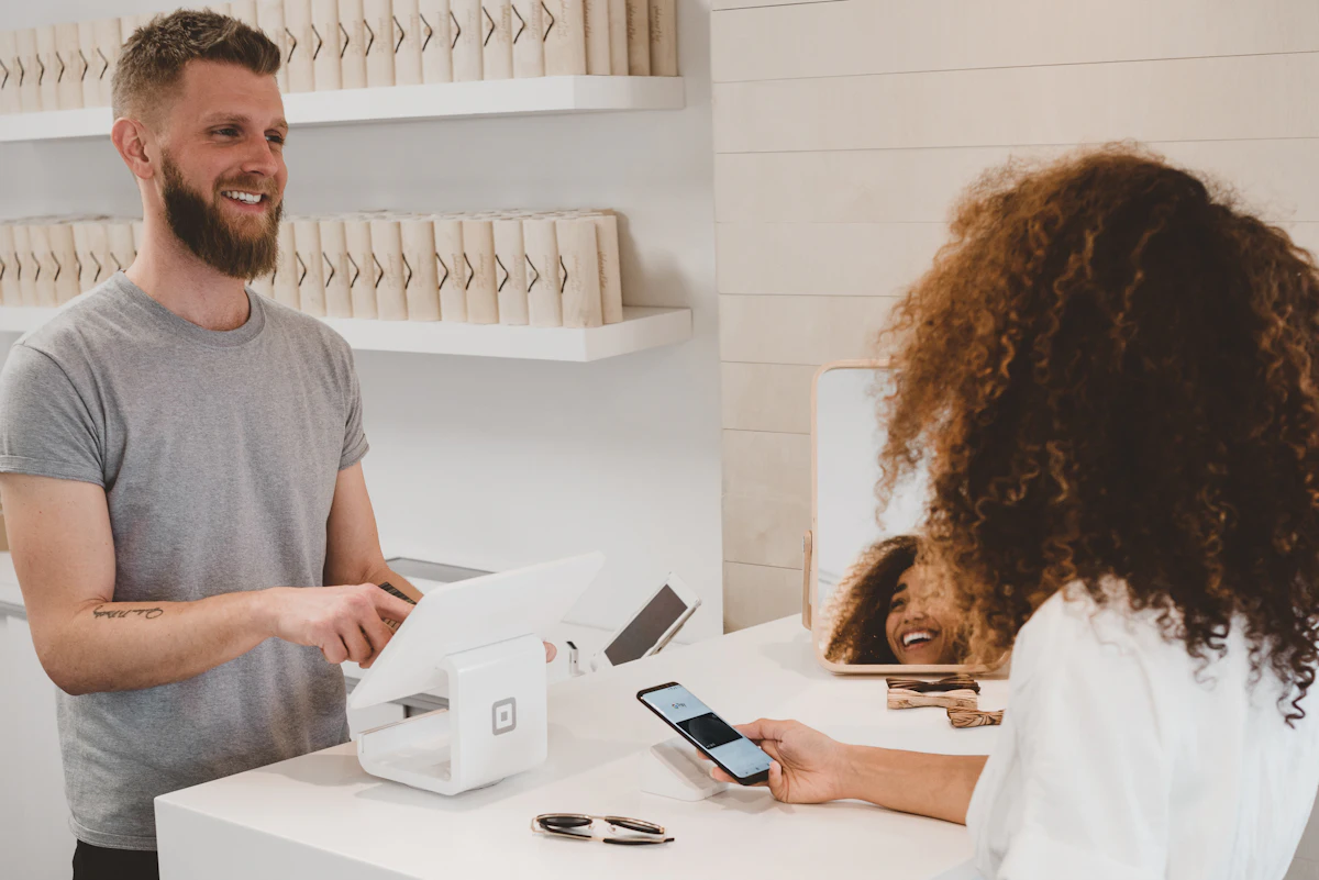 A shop owner smiling with a customer across the counter